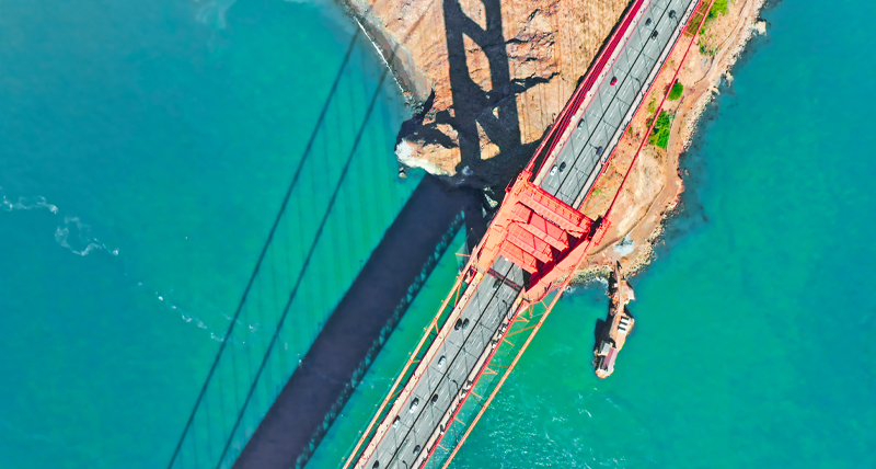 Image aérienne d’un pont suspendu rouge au-dessus d’une eau turquoise, illustrant l’utilisation du Pegasus TRK Evo dans l’évaluation structurelle, l’analyse de tunnels et de viaducs et les inspections de sécurité infrastructurelles.